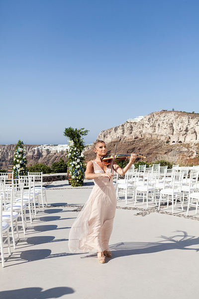 violist playing as bride prepares to walk down the aisle at wedding venue in Santorini venetsanos winery
