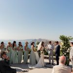 wedding party during ceremony with panoramic sea views at wedding venue in Santorini venetsanos winery