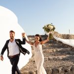 bride and groom walk away hand in hand celebrating at wedding venue in Santorini venetsanos winery