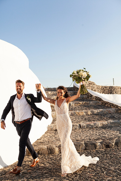 bride and groom walk away hand in hand celebrating at wedding venue in Santorini venetsanos winery