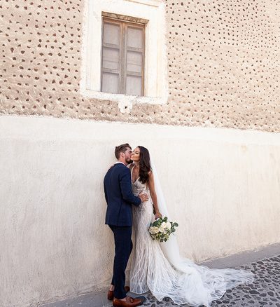 bride and groom kissing outside Santorini wedding venue
