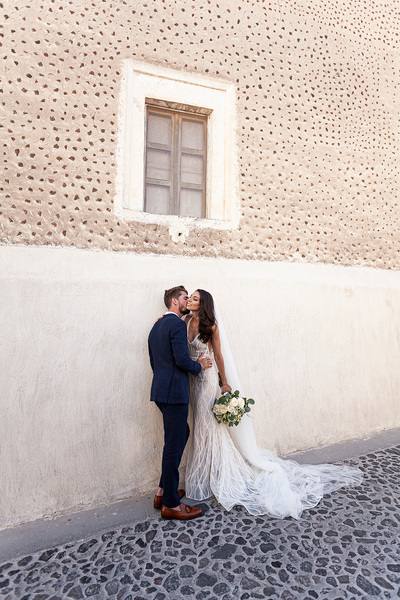 bride and groom kissing outside Santorini wedding venue
