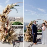 bride and groom stand in front of floral pampas ceremony arch at wedding venue in Santorini venetsanos winery