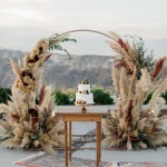 pampas grass and earthy floral arch and wedding cake at wedding venue in Santorini venetsanos winery