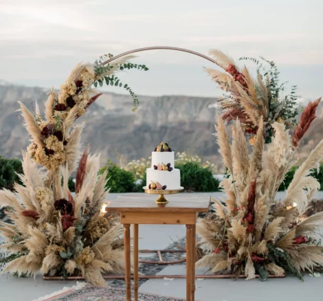 pampas grass and earthy floral arch and wedding cake at wedding venue in Santorini venetsanos winery