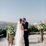 bride and groom kiss and say I do at wedding venue in Santorini venetsanos winery