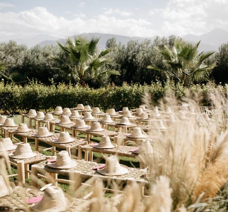 traditional moroccan straw hats sit on benches for the guests during the wedding ceremony at unique wedding venue in morocco kasbah bab ourika