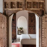 traditional wooden doors open to bedroom suite at unique wedding venue in morocco kasbah bab ourika
