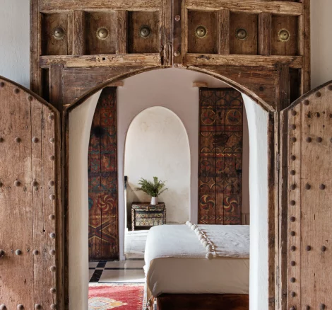 traditional wooden doors open to bedroom suite at unique wedding venue in morocco kasbah bab ourika