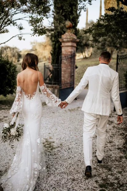 bride and groom walking hand in hand on the grounds of wedding venue in tuscany villa lena