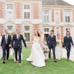 bride and groom walking with bridal party on grounds of chateau wedding venue in france chateau de vallery