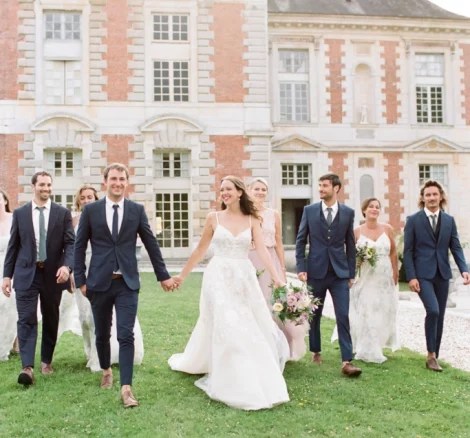 bride and groom walking with bridal party on grounds of chateau wedding venue in france chateau de vallery