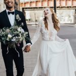 groom holding brides bouquet as they walk outside of unique wedding venue in London 100 Barrington