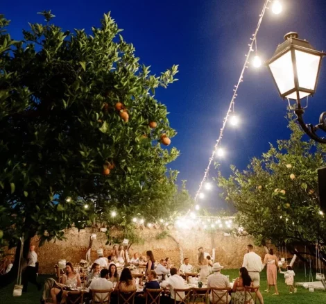 Image of guests outside sitting at tables at wedding venue Metohi Istoria