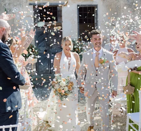 Married couple walking out from ceremony with confetti at wedding venue Metohi Istoria, Crete