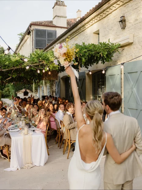Image of married couple entering room with guests at dinner tables at wedding venue Domaine du Rodier