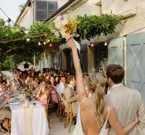 Image of married couple entering room with guests at dinner tables at wedding venue Domaine du Rodier