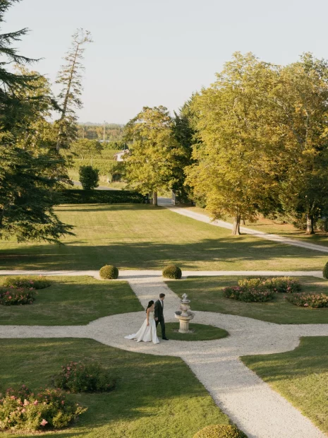 Image of married couple waling through gardens at wedding venue Château de Garde, France