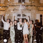 Image of group of people spraying champagne at wedding venue Château de Garde, France