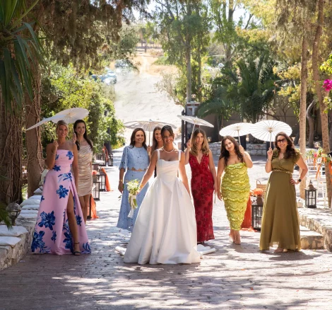 Bride and bridal party walking down path with sun umbrellas at wedding venue Kleopatra, Greece
