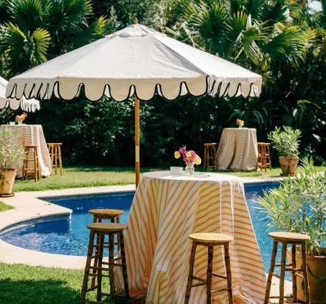 Image of a tall table & chairs around pool with yellow striped tablecloth at wedding venue Finca La Concepción, Spain